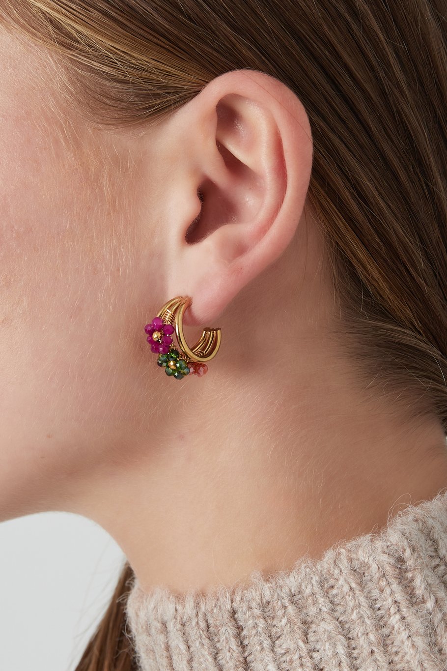 Pendientes de aro dorado con flores en abalorios de colores, vista frontal.
