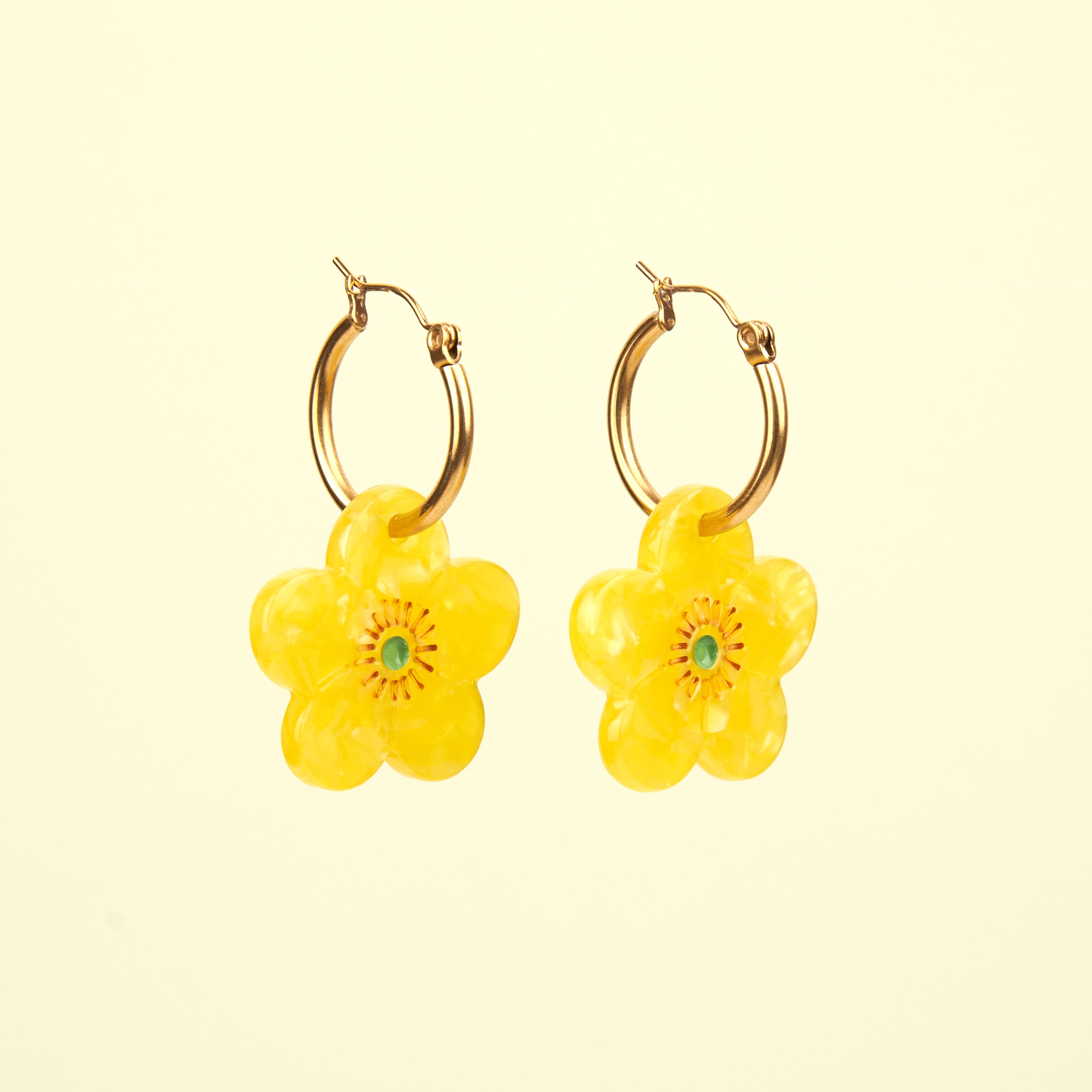 Pendientes florales amarillos de Coucou Suzette fotografiados sobre fondo amarillo.
