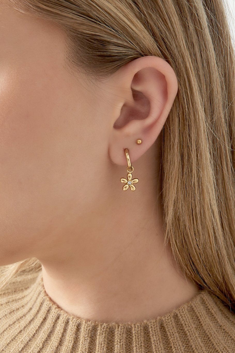 Pendientes dorados con colgante de flor y centro de circonita, vista frontal.