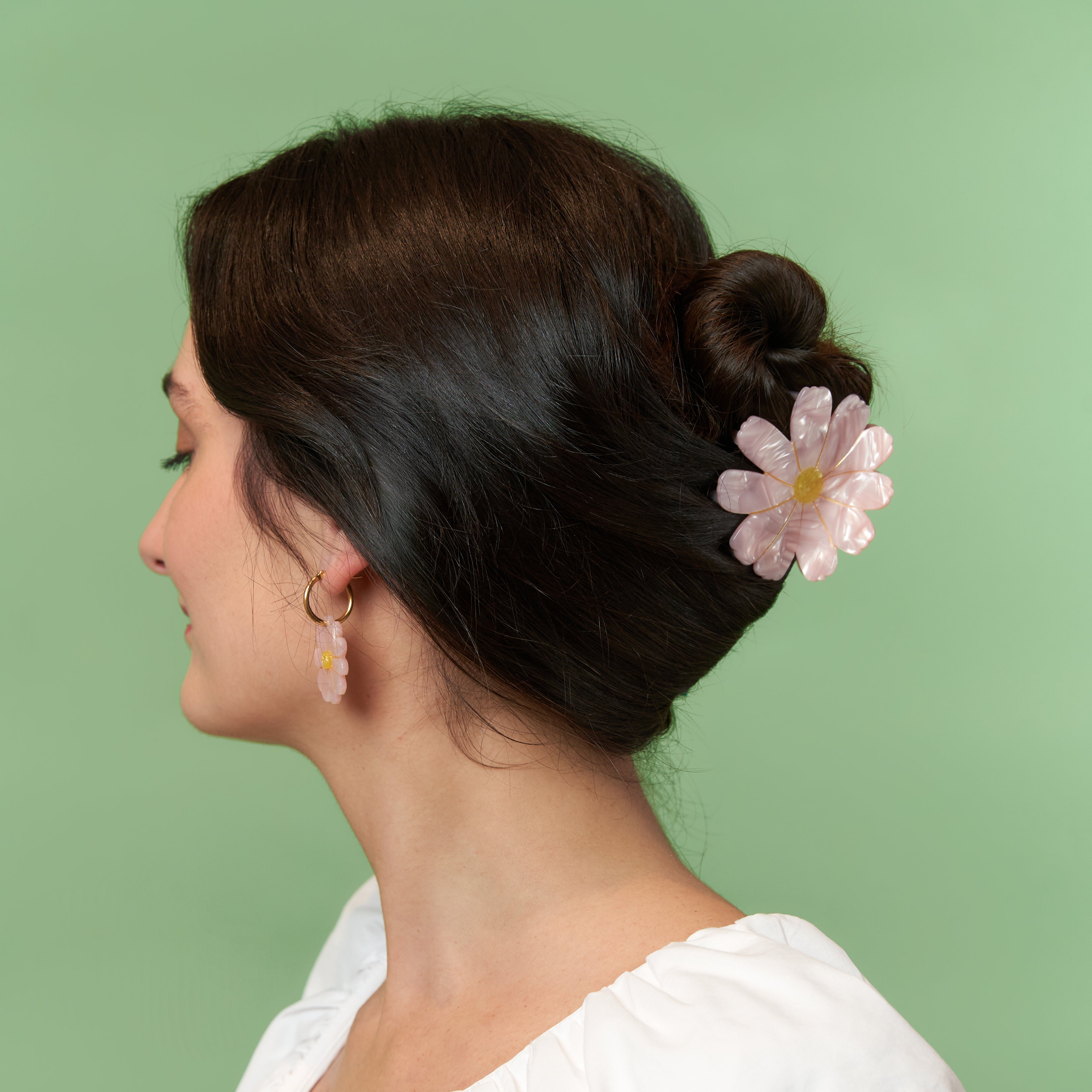 Mujer con moño bajo sujetado con una pinza Coucou Suzette en forma de flor rosa.