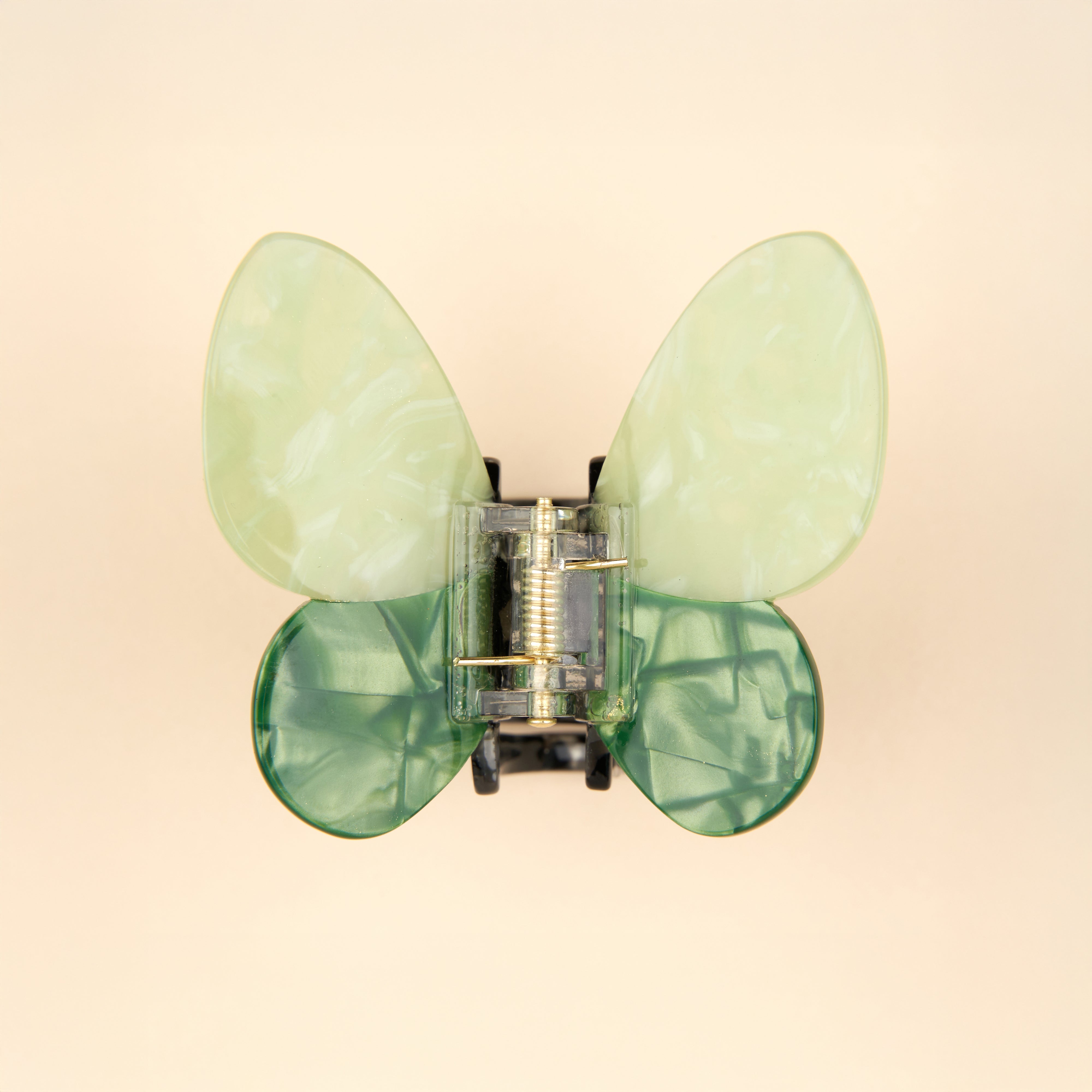 Detalle de pinza mariposa verde en fondo beige claro Coucou Suzette