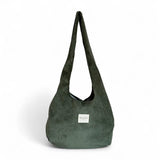 Bolsa ovalada de pana verde oliva con etiqueta De La Mur, vista frontal.