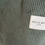 Detalle del tejido de pana verde oliva con etiqueta frontal de la marca De La Mur.