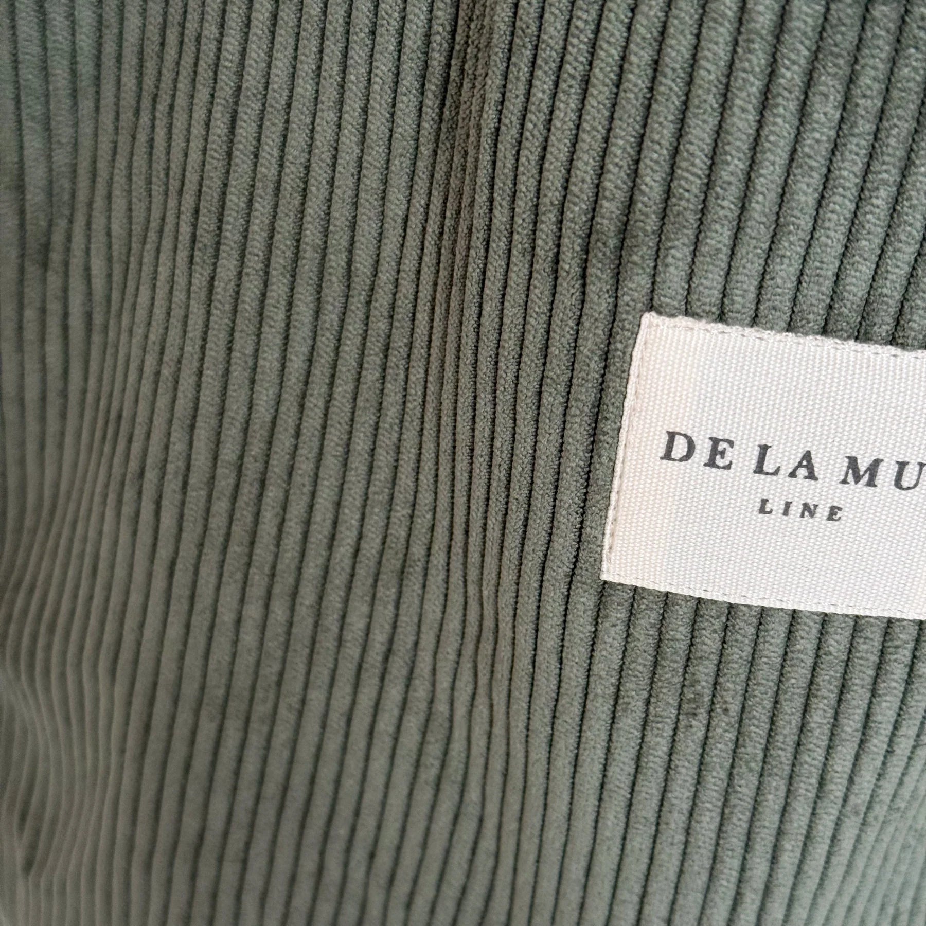 Detalle del tejido de pana verde oliva con etiqueta frontal de la marca De La Mur.