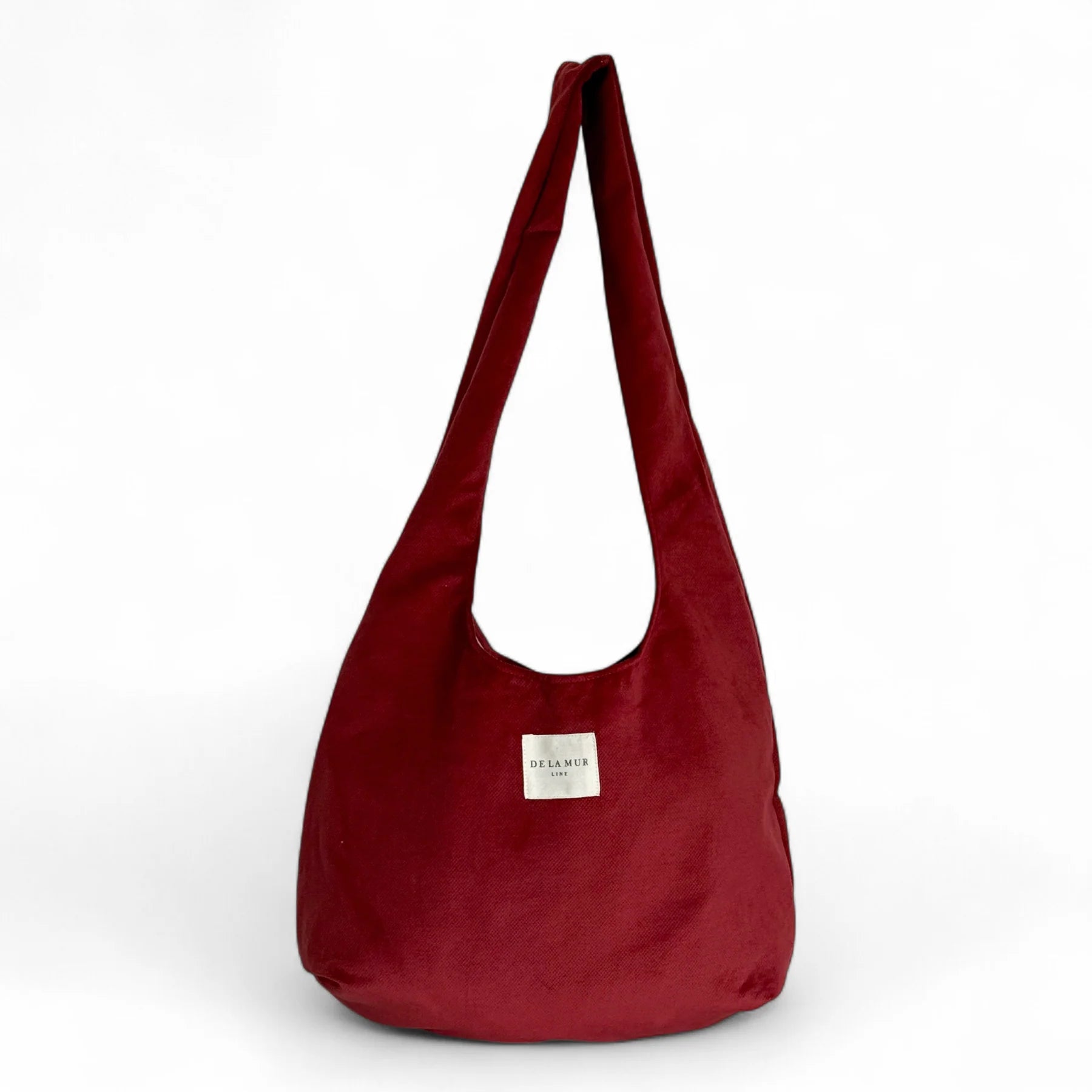 Bolsa ovalada de terciopelo granate con etiqueta De La Mur, vista frontal.