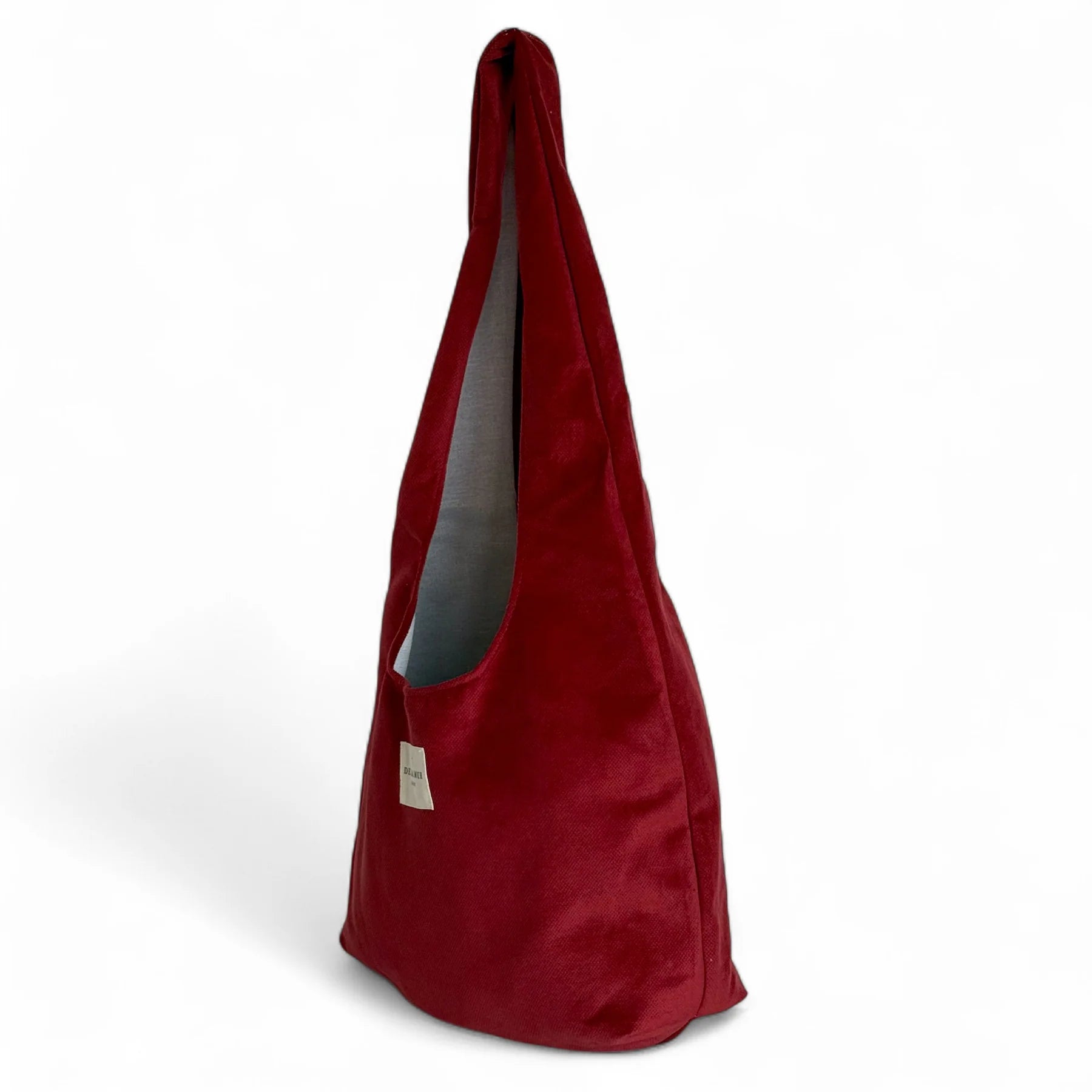 Bolsa ovalada de terciopelo granate, vista lateral mostrando su forma alargada.