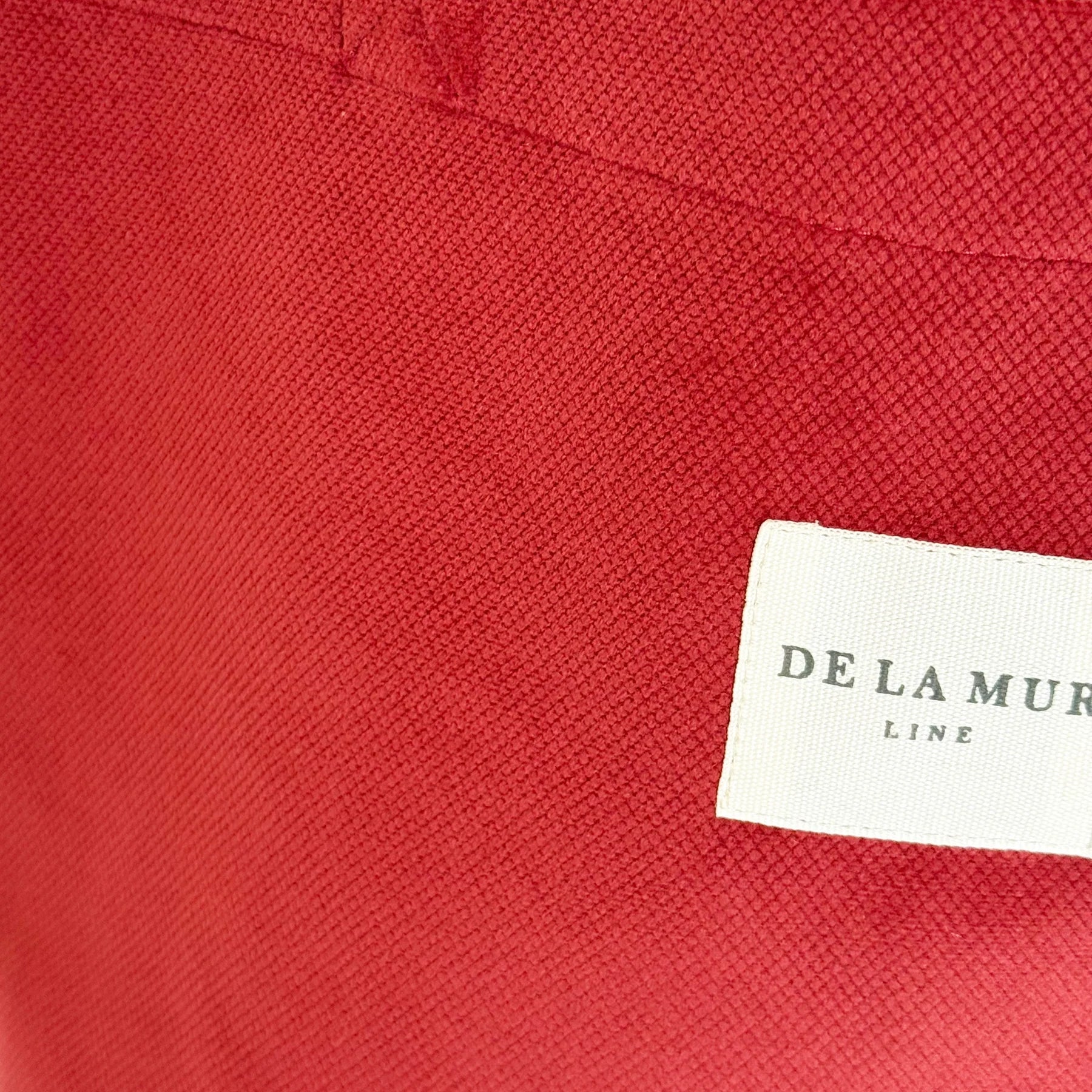 Detalle del tejido de terciopelo granate y etiqueta frontal de la marca De La Mur