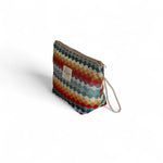 Neceser grande con diseño geométrico de colores vivos y asa lateral de cordón beige.