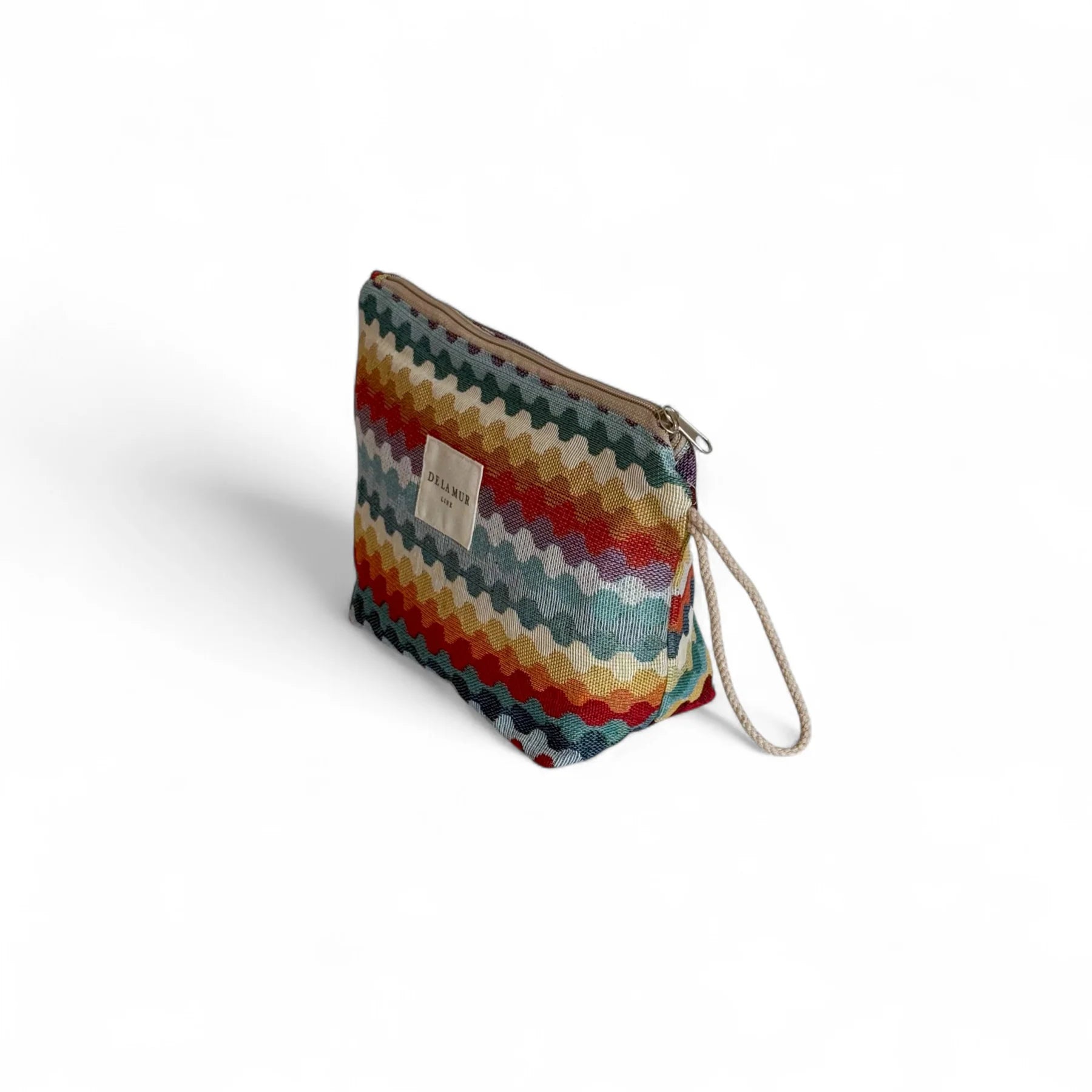 Neceser grande con diseño geométrico de colores vivos y asa lateral de cordón beige.