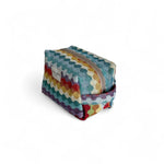 Neceser de estampado geométrico multicolor con cremallera y asa lateral, vista lateral.