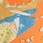 Puzzle "Passer au Fromage" con piezas sueltas sobre fondo naranja