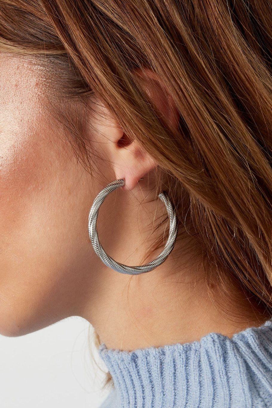 Modelo con pendientes de aro trenzado plateado, vista lateral

