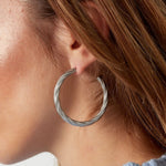 Modelo con pendientes de aro trenzado plateado, vista lateral

