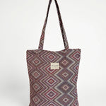 Bolsa shopper de jacquard con estampado geométrico en tonos lila y rosa, vista frontal.