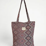 Bolsa shopper de jacquard con estampado geométrico en tonos lila y rosa, vista frontal.