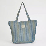 Bolsa shopper de jacquard de rayas azules llevada al hombro.