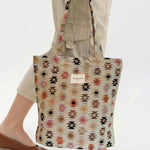 Bolsa tote de jacquard con estampado étnico siendo sostenida por una persona.