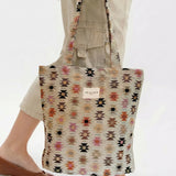 Bolsa tote de jacquard con estampado étnico siendo sostenida por una persona.