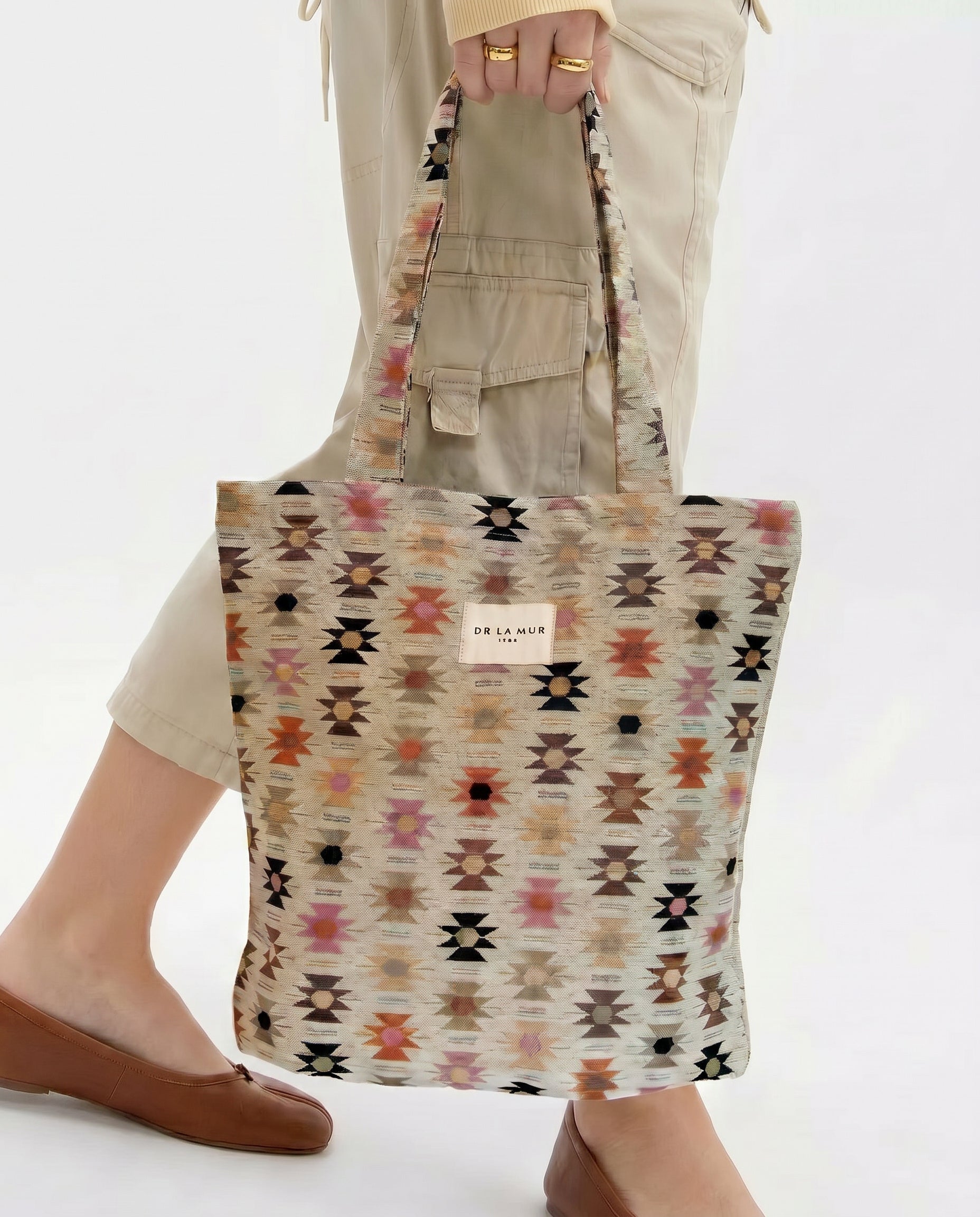 Bolsa tote de jacquard con estampado étnico siendo sostenida por una persona.