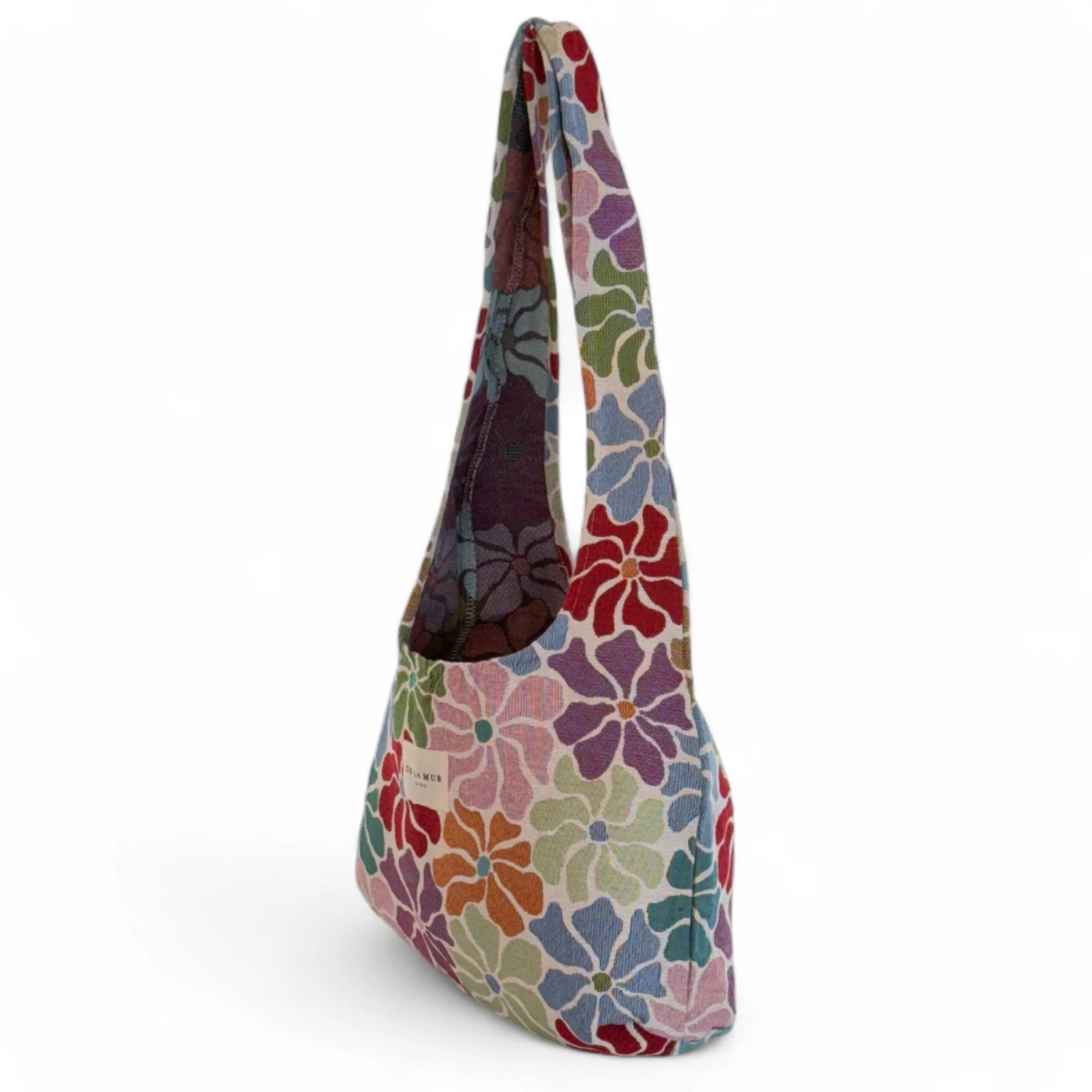 Vista lateral de la bolsa floral con asas anchas y fondo blanco.