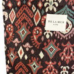 Detalle de tejido grueso jacquard con motivos granates y etiqueta De La Mur