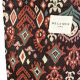 Detalle de tejido grueso jacquard con motivos granates y etiqueta De La Mur