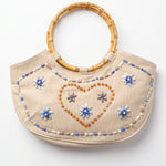Imagen 1: Bolso vintage color crema con asas de bambú y decoración de cuentas en forma de flores y corazón.
