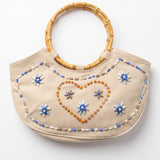 Imagen 1: Bolso vintage color crema con asas de bambú y decoración de cuentas en forma de flores y corazón.