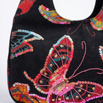 Detalle del bordado de mariposa con lentejuelas y cuentas sobre bolso vintage negro.