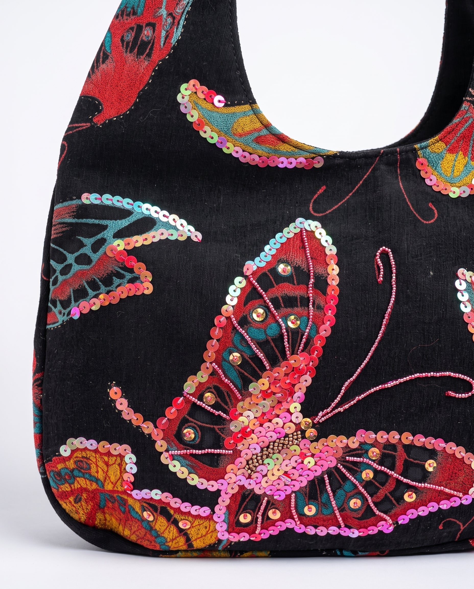 Detalle del bordado de mariposa con lentejuelas y cuentas sobre bolso vintage negro.