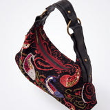 Vista lateral del bolso vintage negro con asa regulable y detalles bordados.