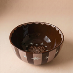 Bowl de cerámica marrón con estrellas blancas y diseño de sol en el interior.