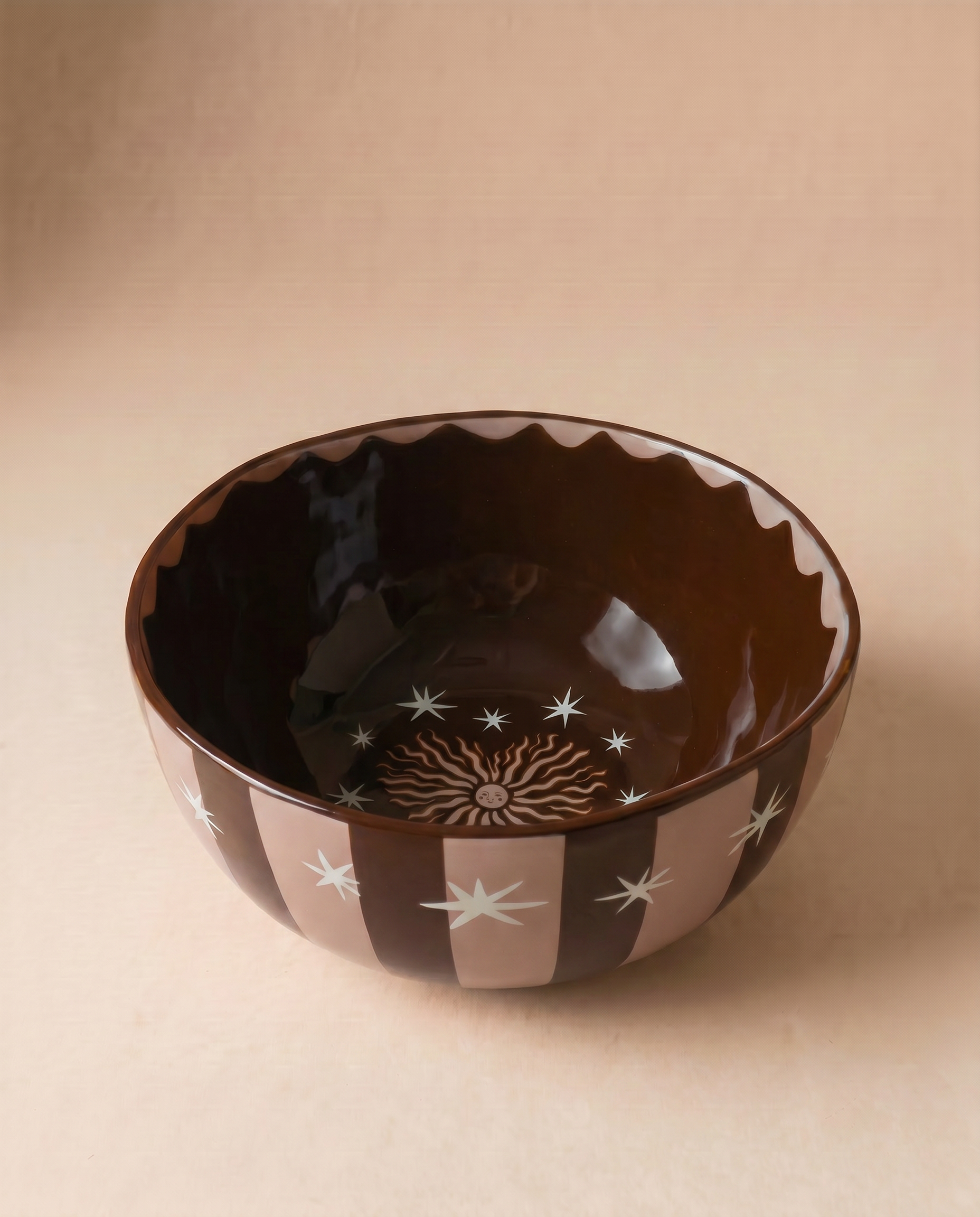 Bowl de cerámica marrón con estrellas blancas y diseño de sol en el interior.