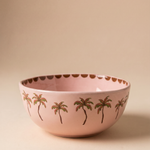 Bowl de cerámica rosa con estampado de palmeras alrededor del borde.