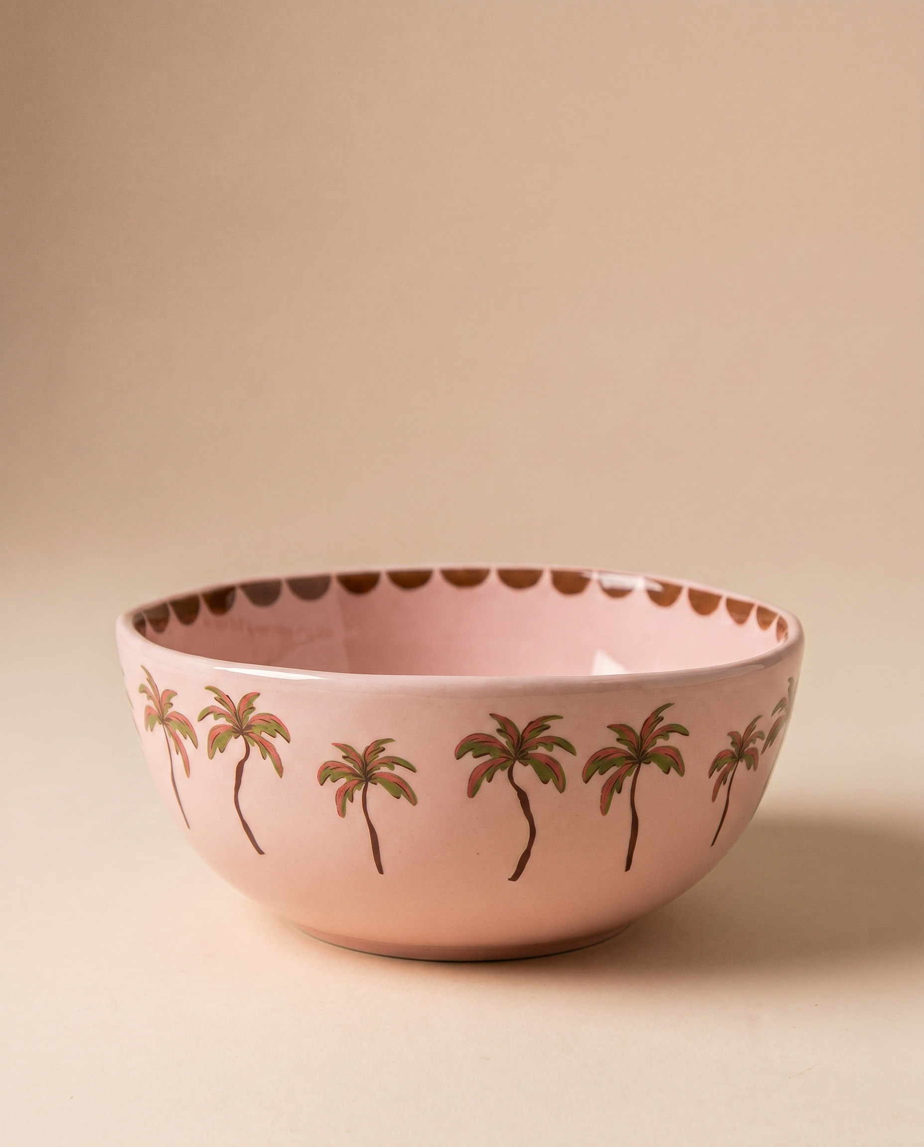 Bowl de cerámica rosa con estampado de palmeras alrededor del borde.