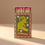 Caja de cerillas largas A Dopo con ilustración de un cocodrilo sobre fondo verde.