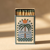 Caja de cerillas largas A Dopo con ilustración de una palmera y paisaje mediterráneo.