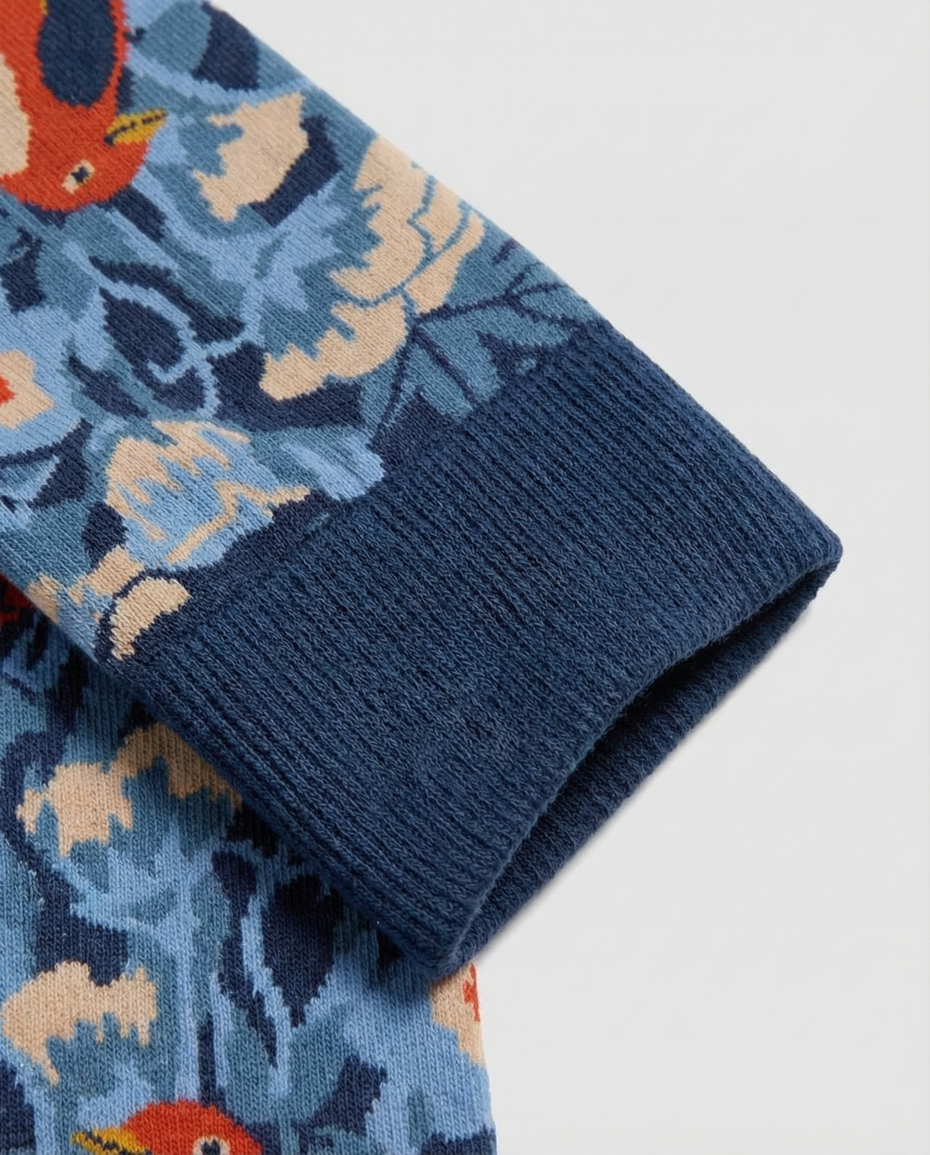 Detalle del tejido de calcetines florales con pájaros y costuras planas