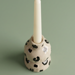 Candelabro de cerámica con una vela blanca colocada.
