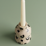 Candelabro de cerámica con una vela blanca colocada.