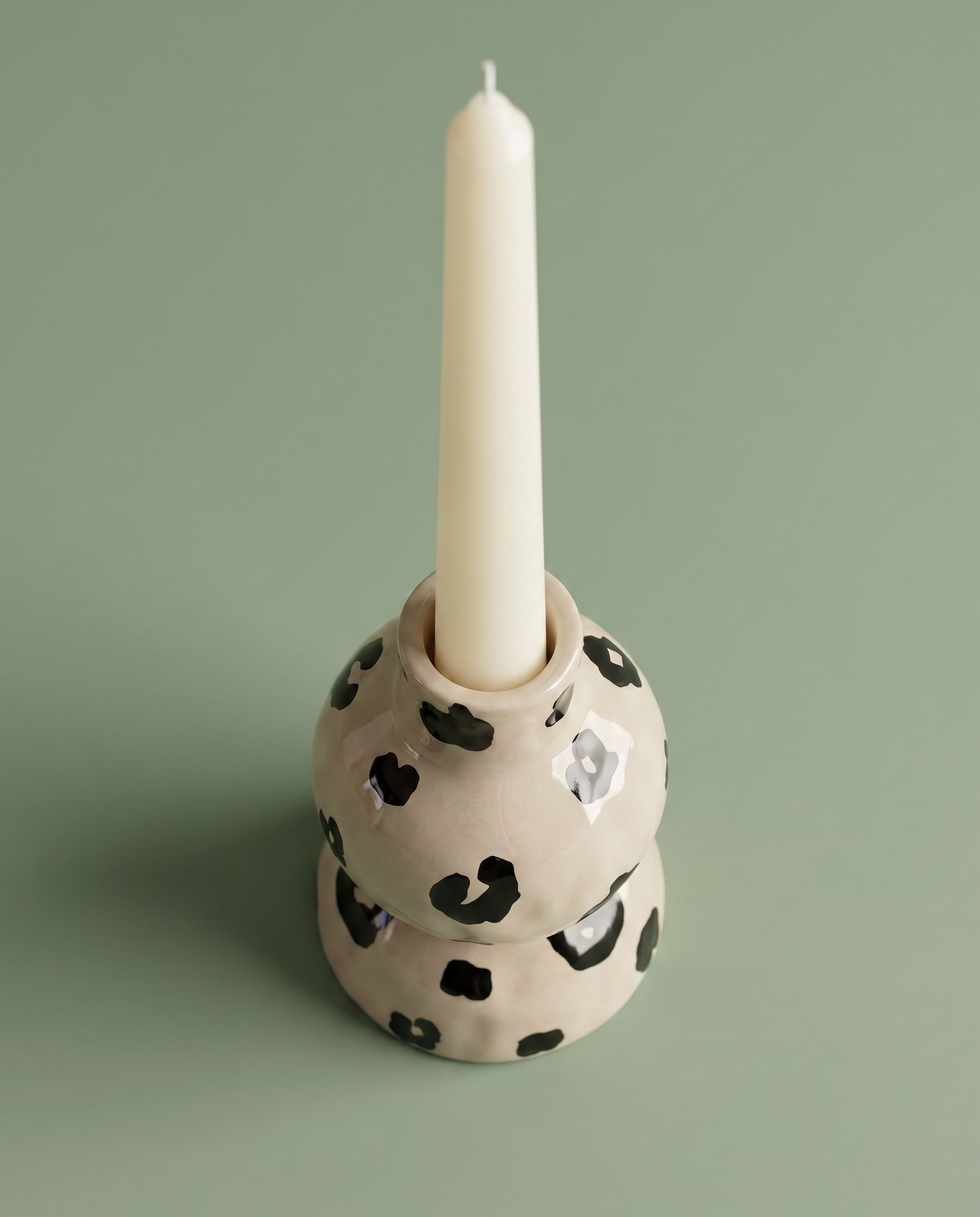 Candelabro de cerámica con una vela blanca colocada.