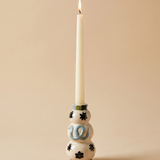 Candelabro serpiente azul de cerámica con vela blanca sobre fondo neutro.