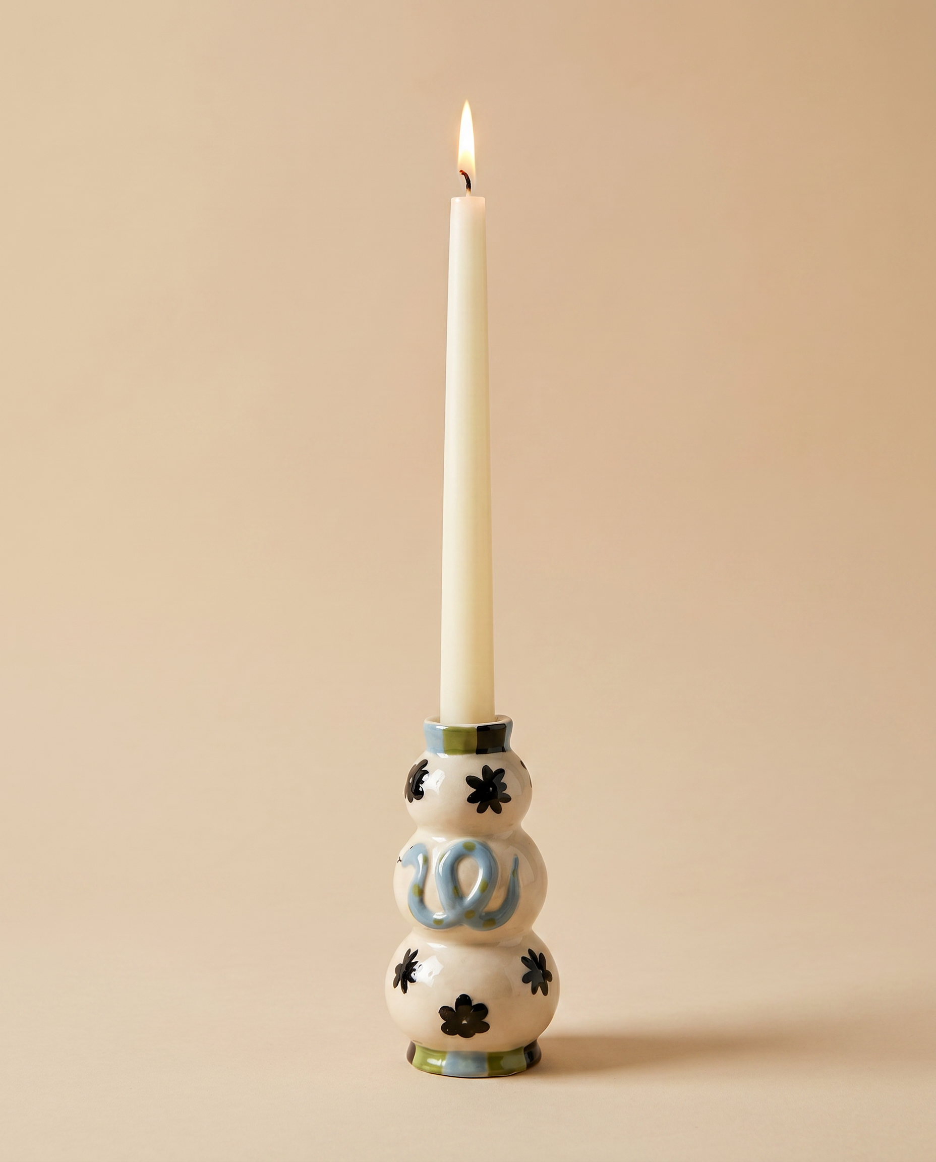 Candelabro serpiente azul de cerámica con vela blanca sobre fondo neutro.