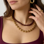 Mujer con collar de doble vuelta de cuentas burdeos y doradas.