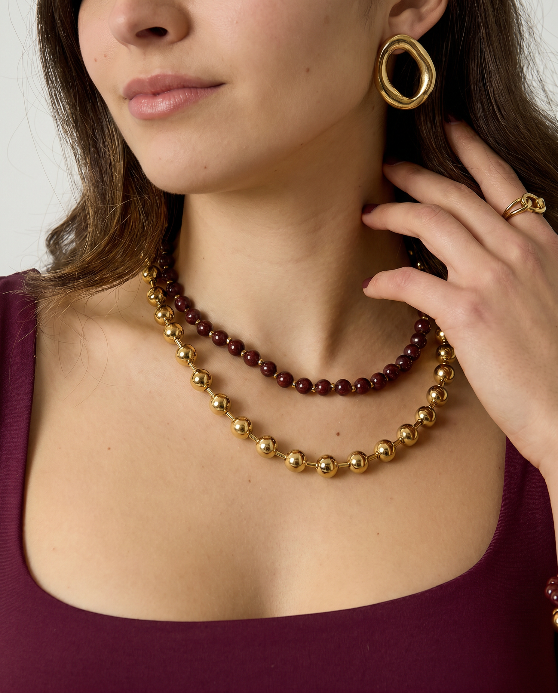 Mujer con collar de doble vuelta de cuentas burdeos y doradas.