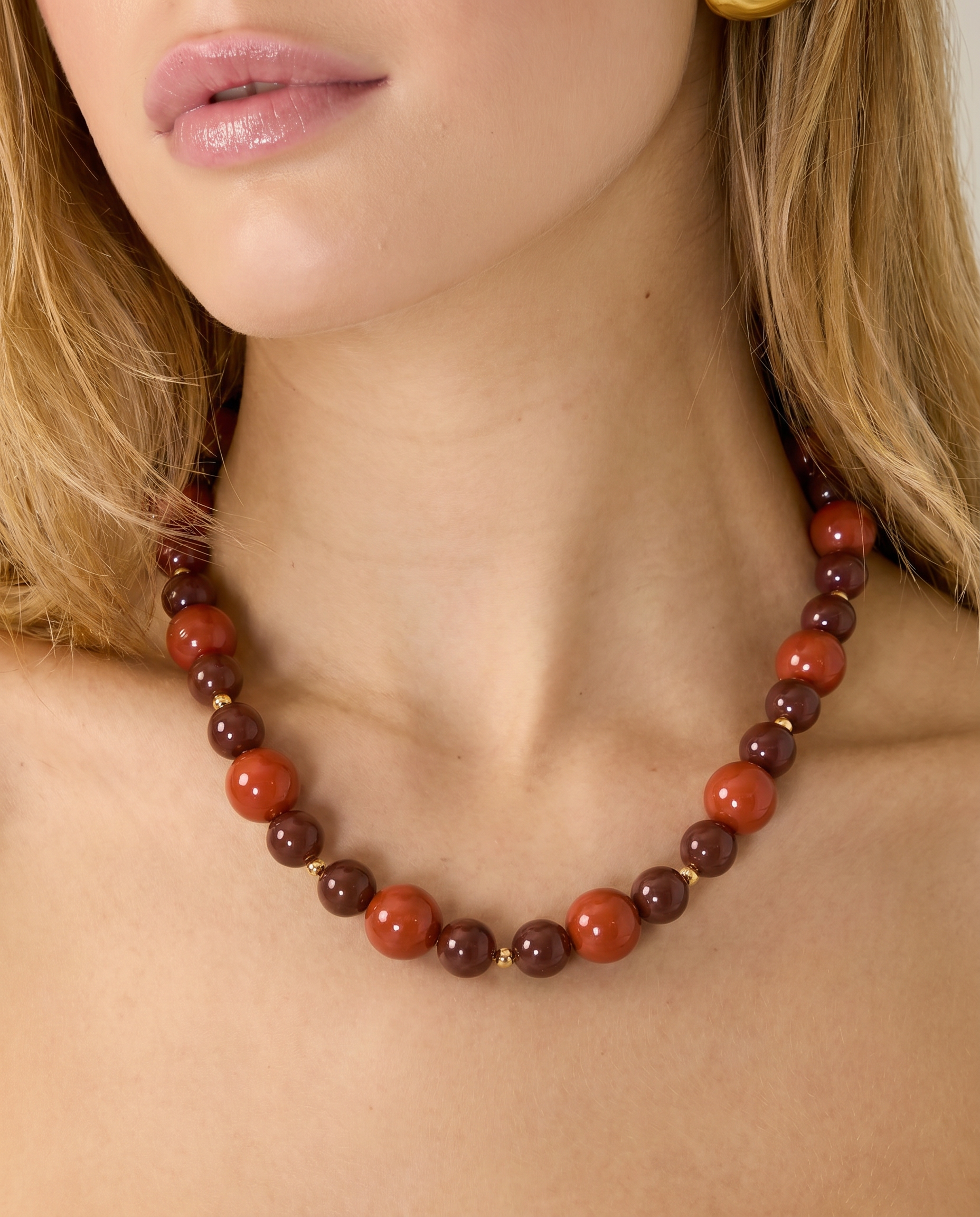 Mujer llevando un collar de cuentas marrones y terracota.