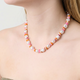 Mujer llevando un collar de perlas con cuentas de colores estilo Y2K.