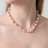 Collar de perlas irregulares con cuentas de colores en tonos rosa, naranja y blanco.