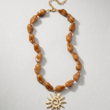 Collar de cuentas acrílicas color ámbar con colgante de sol dorado.