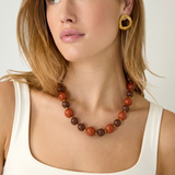 Collar de bolas acrílicas en tonos tierra combinado con un look neutro.